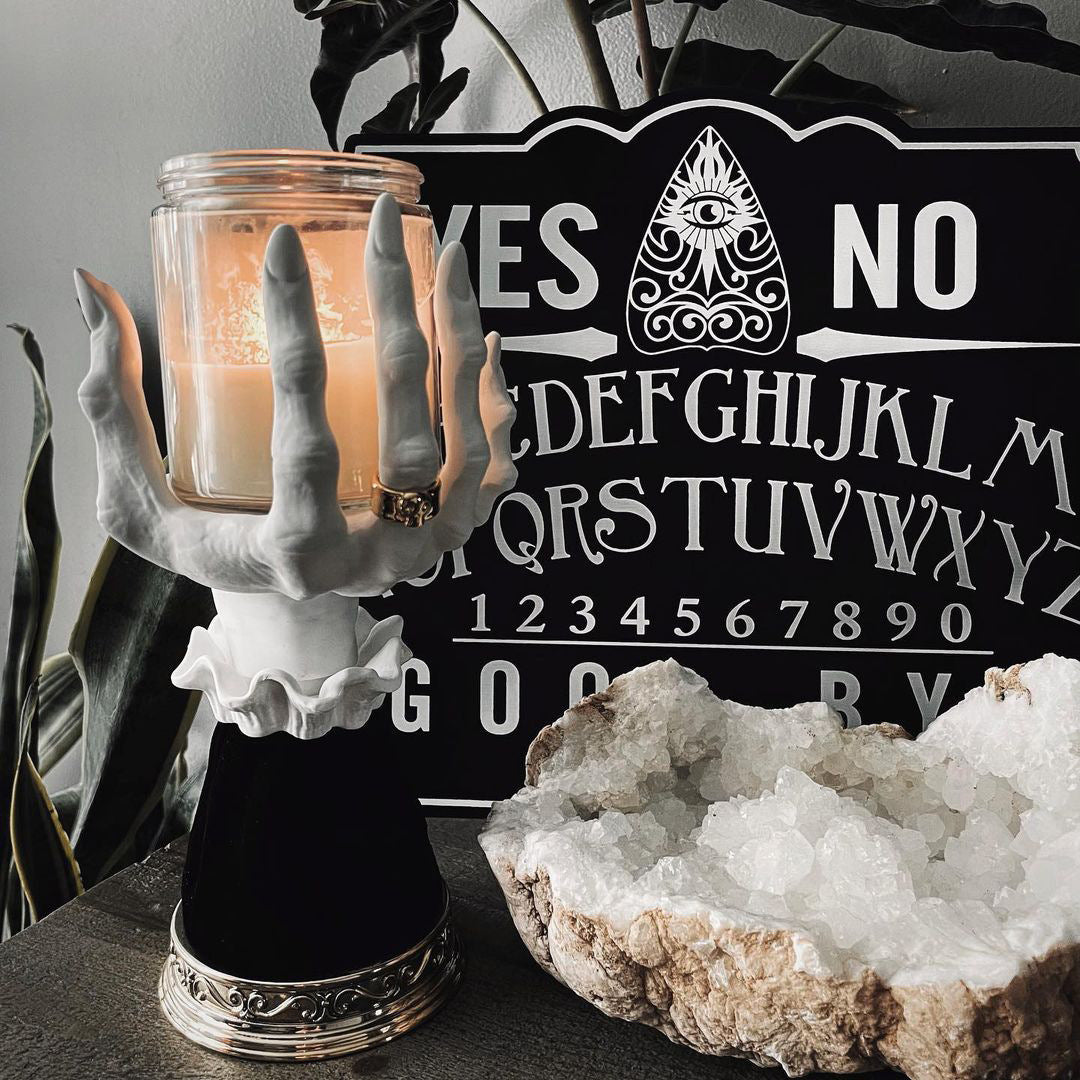 Halloween seat candlestick with a spooky hand design holding a lit candle for festive decor