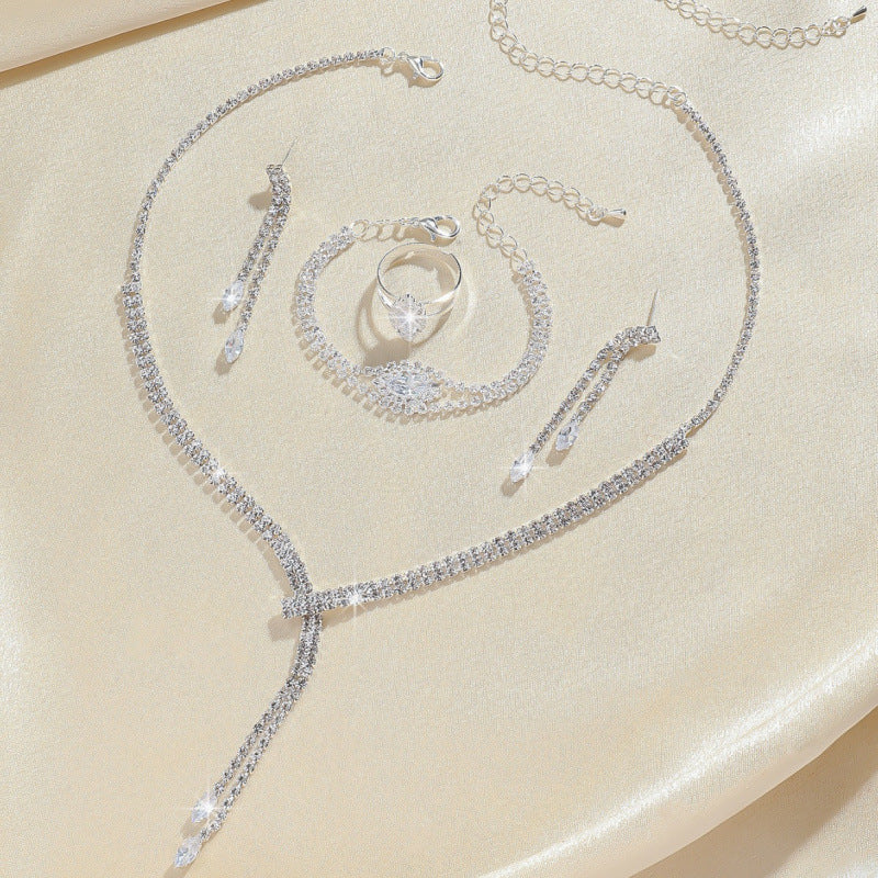 Elegant wedding zirconium jewelry set featuring necklace, bracelet, earrings, and ring on satin fabric